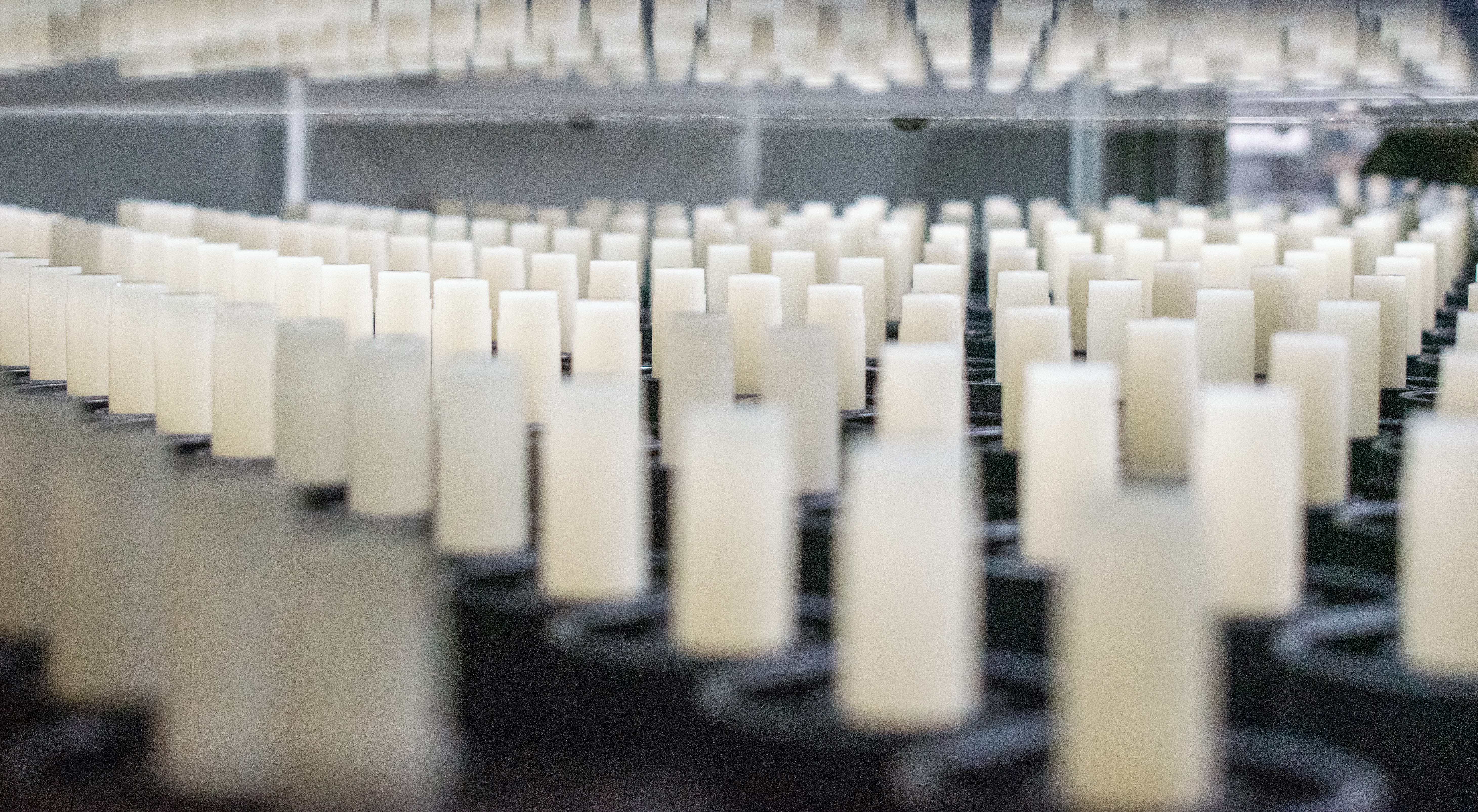 Seemingly endless rows of white lip balm tubes fill a factory floor. 