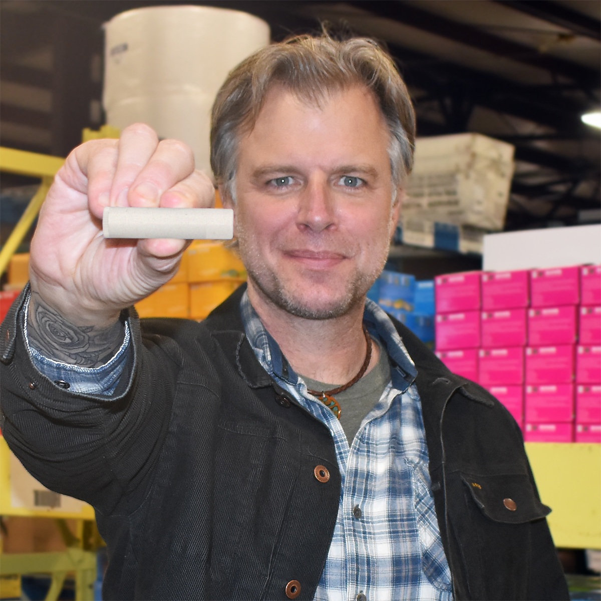 Eco Lips founder Steve Shriver holds a tube of lip balm toward the camera.