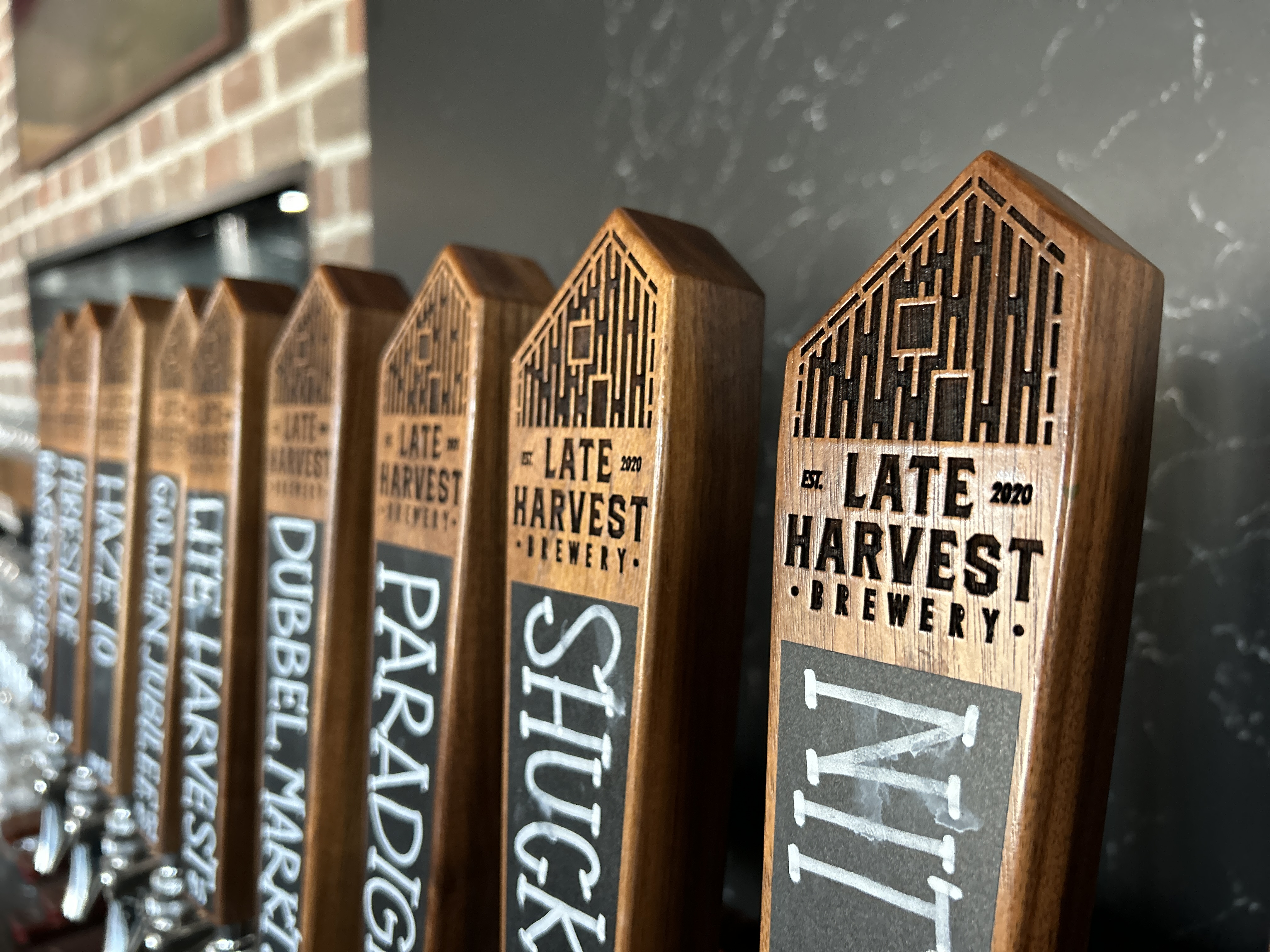 A line of tap handles show the brewery name Late Harvest Brewery carved into the wood.