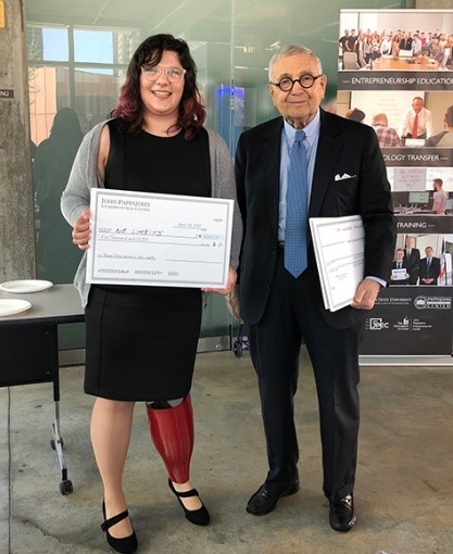 Erica smiling while holding an oversized check next to an older gentleman