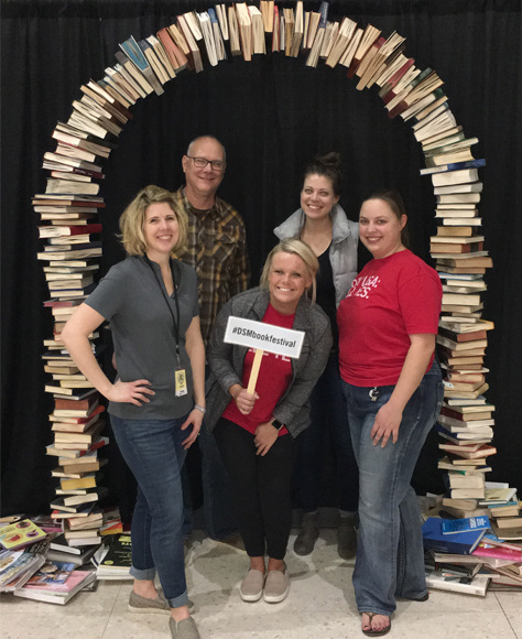 DSM team setting up the book festival stop to take a team picture under a book arch