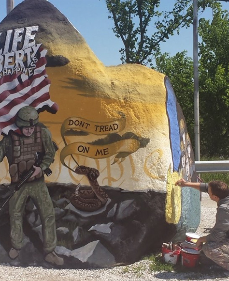 A volunteer painting a mural on the freedom rock