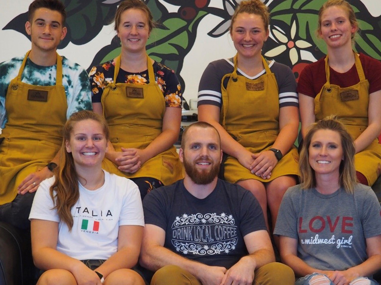 Employees of Euphoria Coffee sitting together in front of a mural.