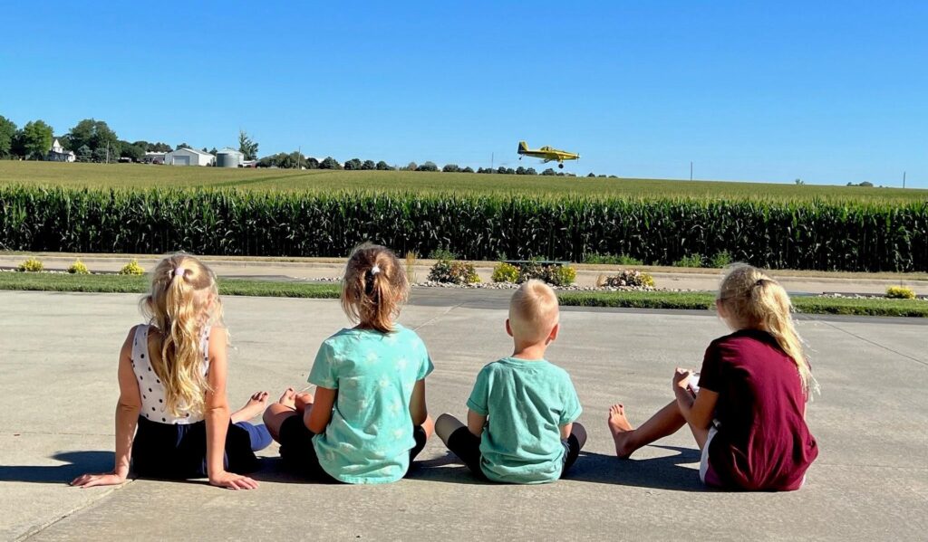 kids sitting by a corn field