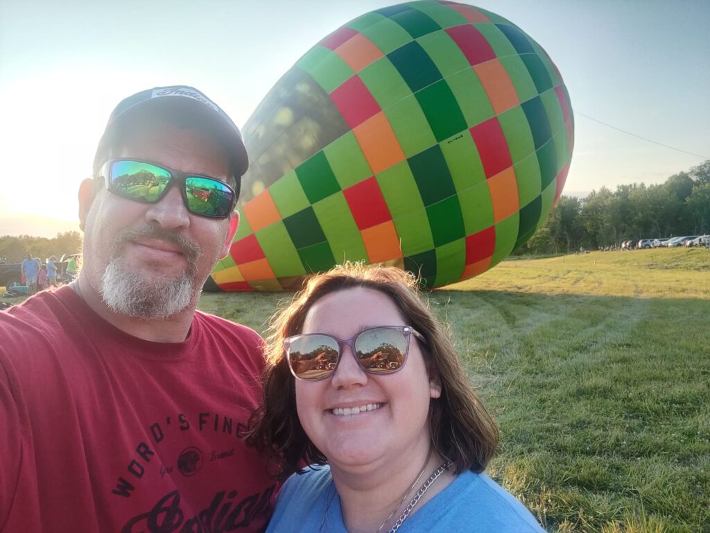 a couple posing in front of a hot air balloon