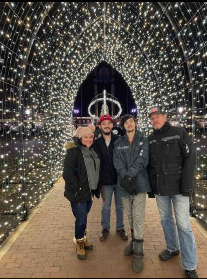 a family posing under an arch of holiday lights