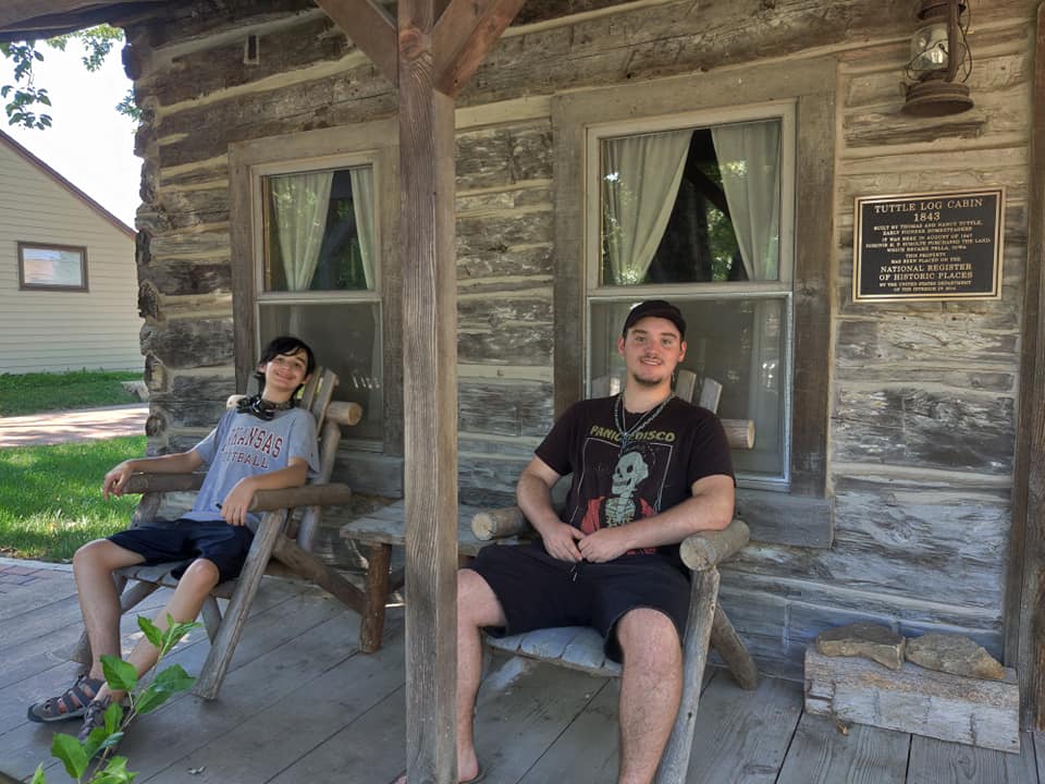 two young men sitting on a cabin porch
