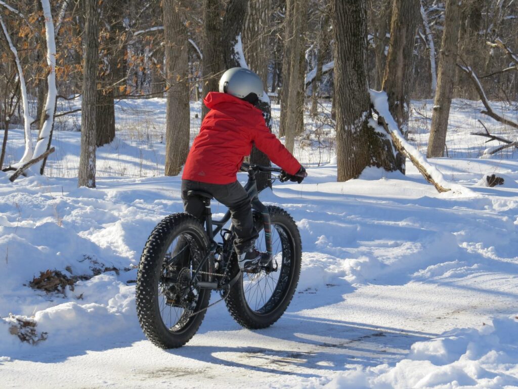 cyclist wearing a red coat biking in the snow
